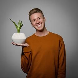 A man is holding a potted plant in his hand and smiling.