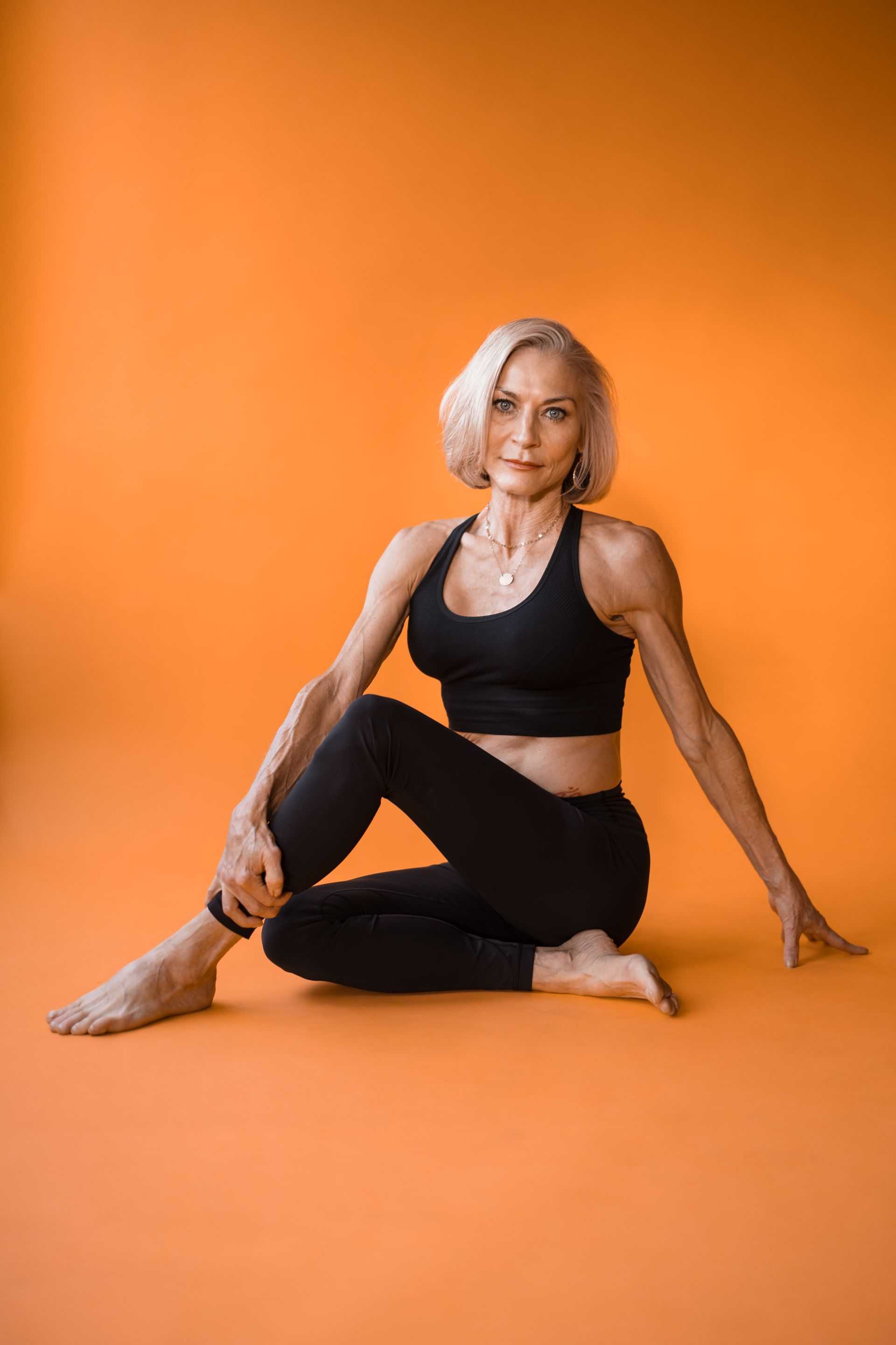 A woman is sitting on the floor in a yoga pose.