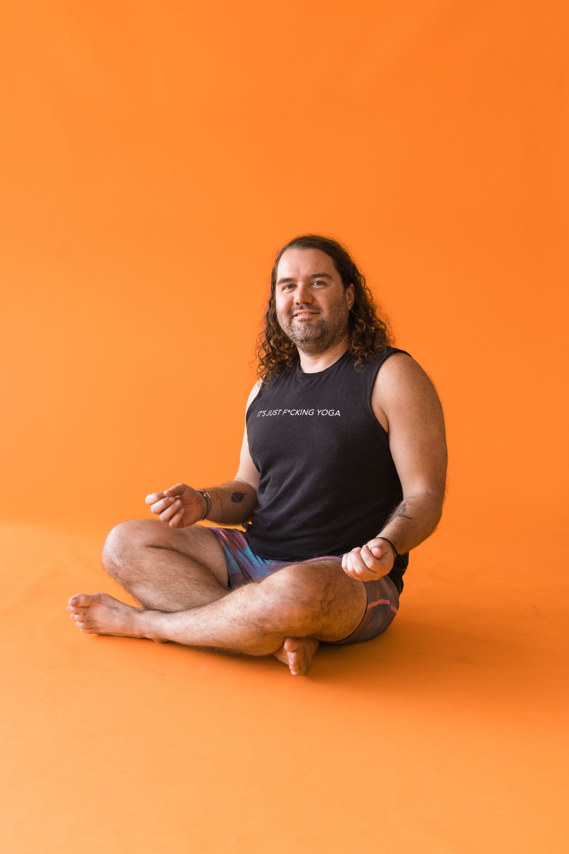 A man is sitting on the floor in a lotus position.