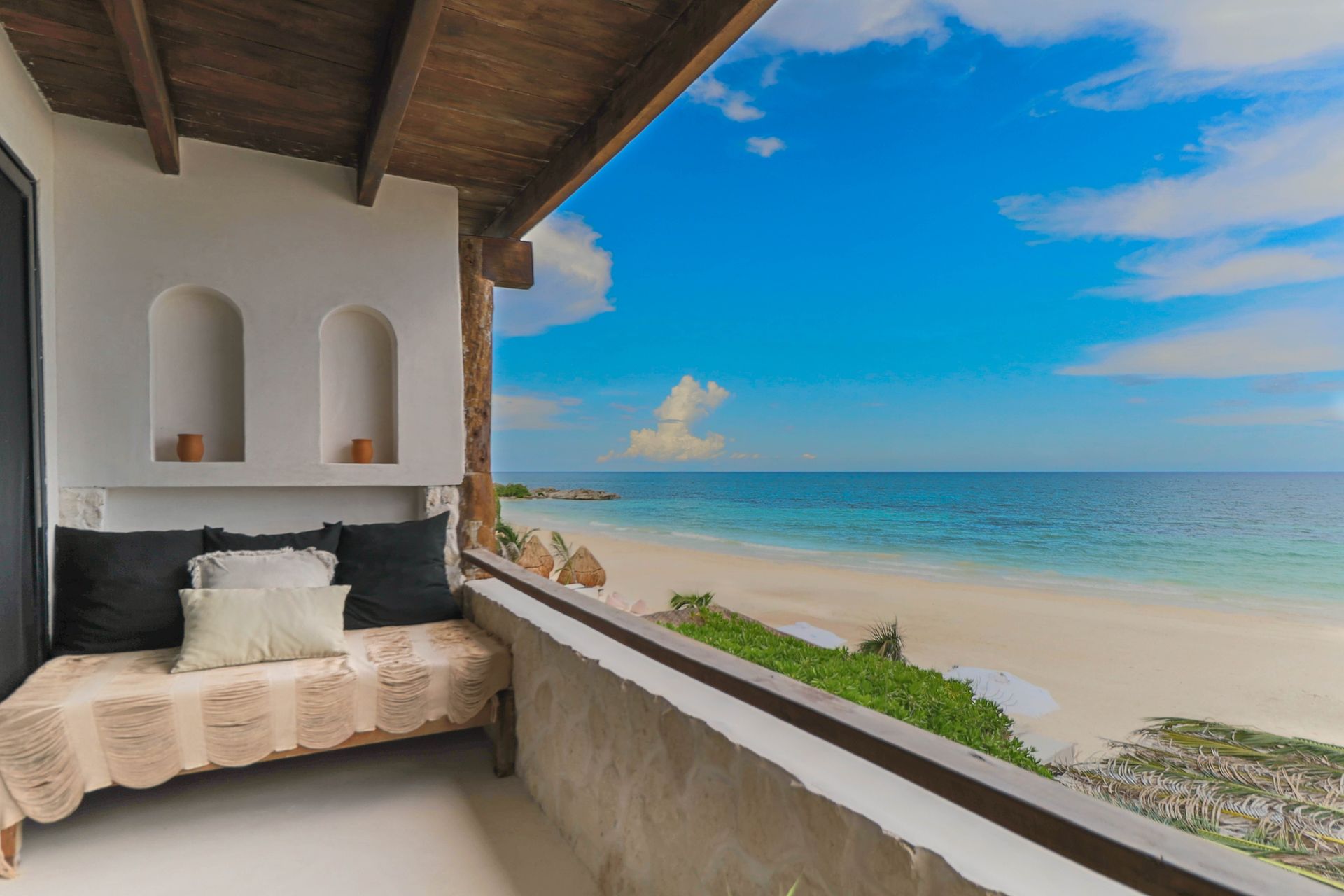 A balcony with a bed and a view of the ocean.