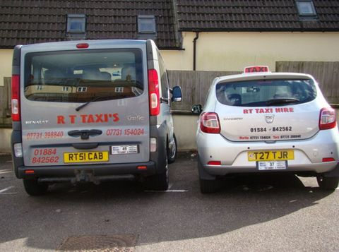 RT Taxi Hire branded grey van and white car