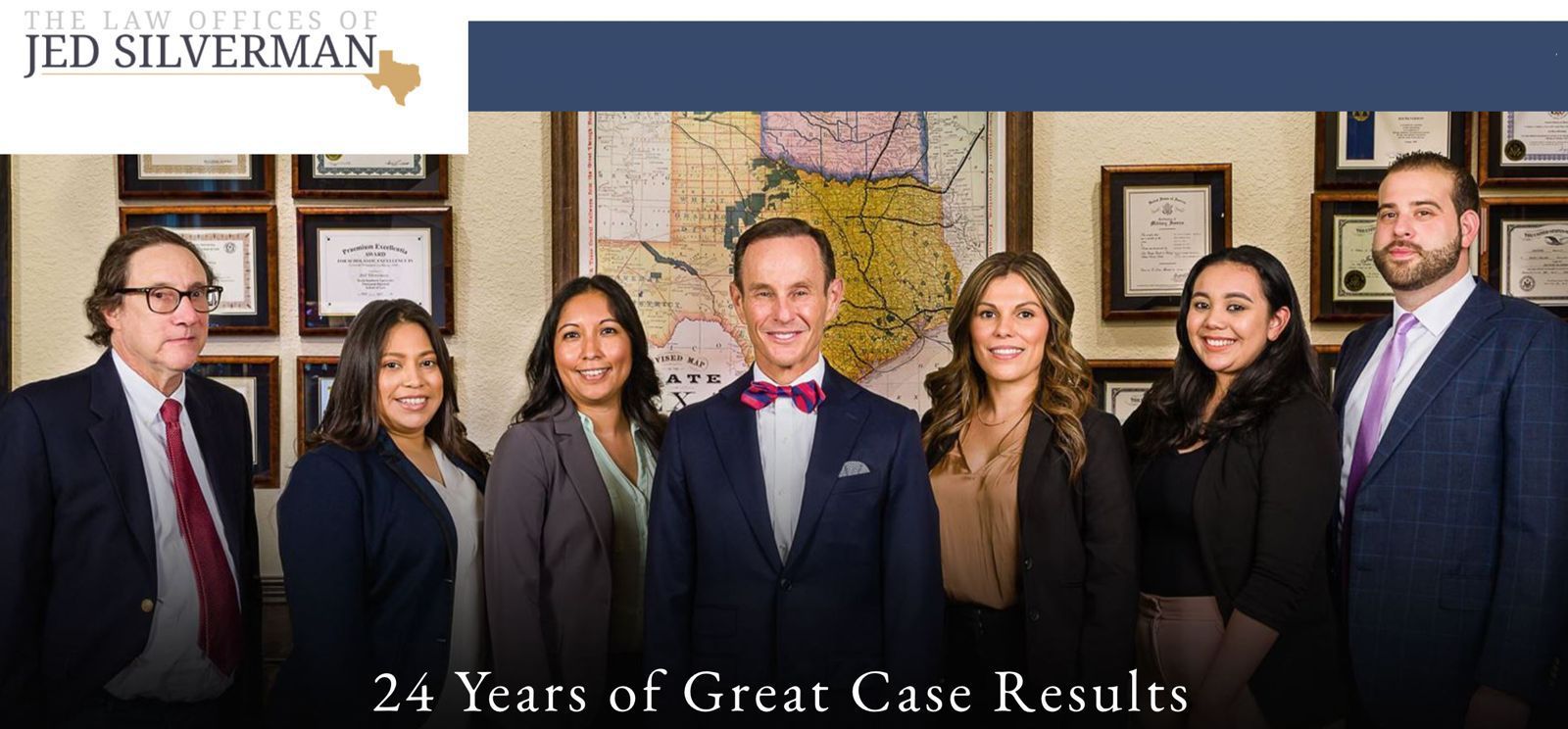 Law office team standing together, smiling.  Includes Jed Silverman, and women and men in suits, in front of a map.