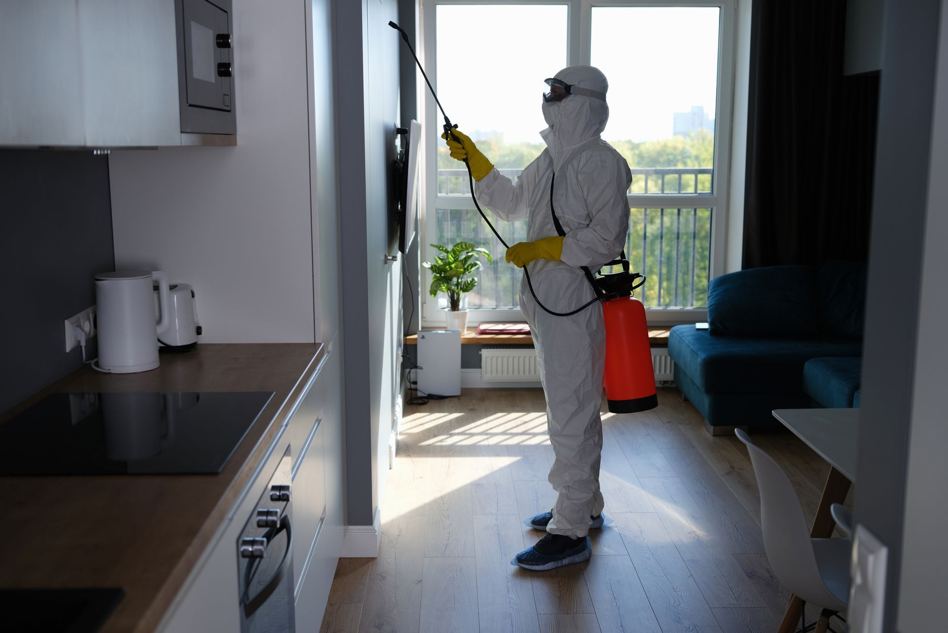 A worker in a protective suit cleans the room of cockroaches and rats with a spray gun.