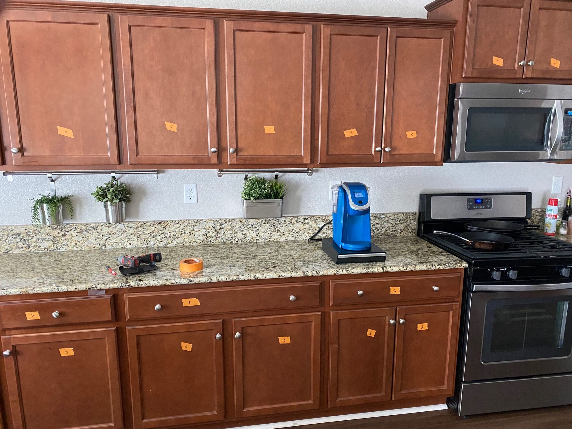 Kitchen with brown cabinets, granite countertops, blue coffee maker, and stainless steel stove and microwave.