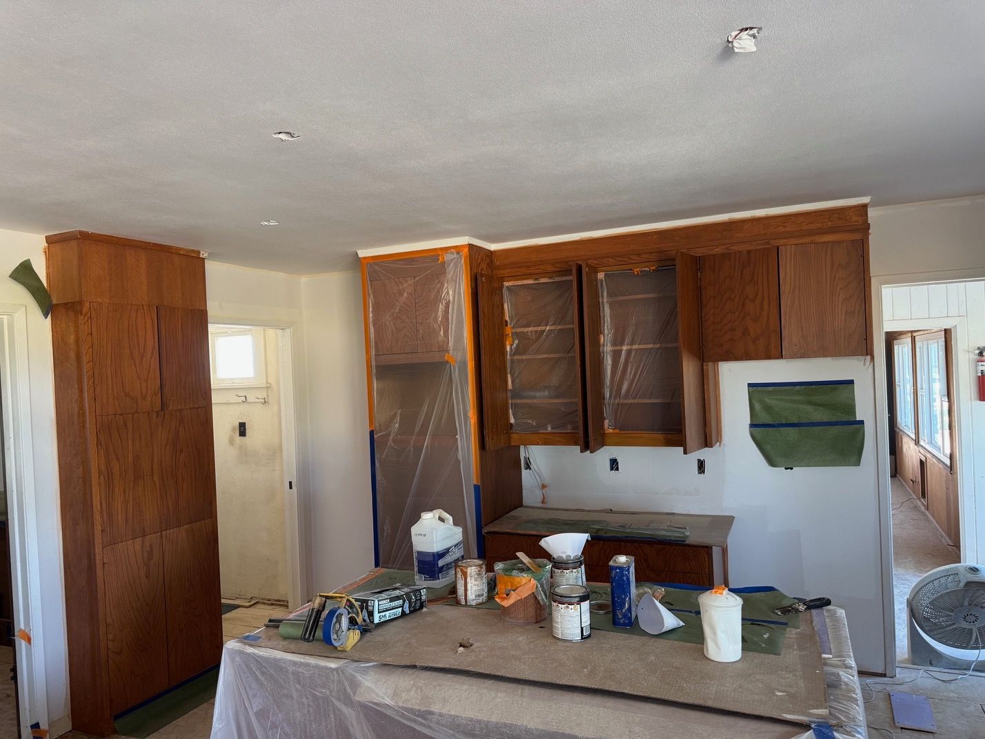 Kitchen under renovation with unfinished cabinets, countertop tools, and a white stove on the right