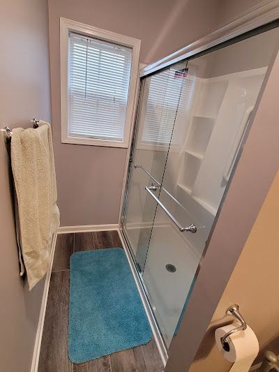 A bathroom with a sliding glass shower door and a blue rug.