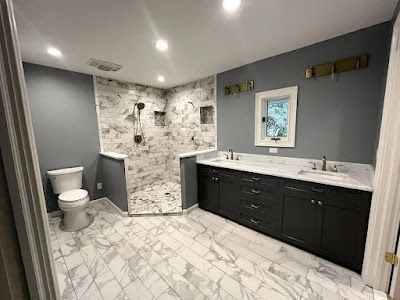 A bathroom with two sinks , a toilet , and a walk in shower.