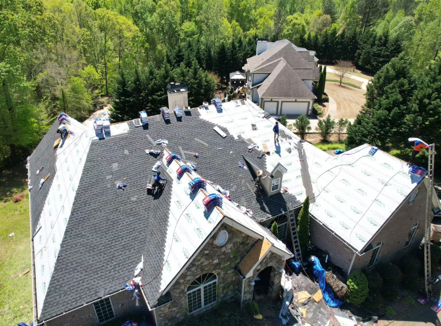 An aerial view of a large house with a roof being installed.