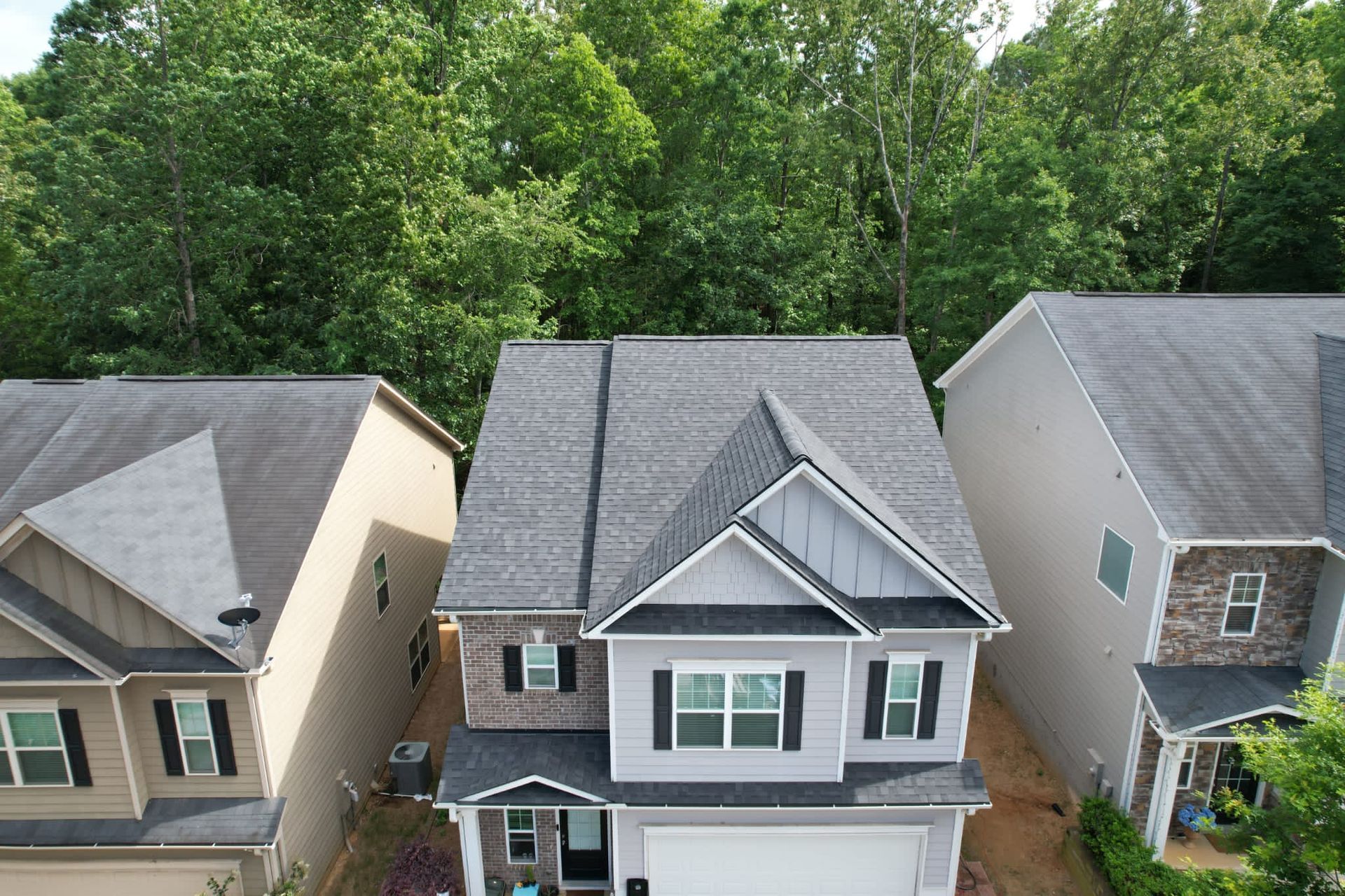 An aerial view of a house with a roof that is surrounded by trees.