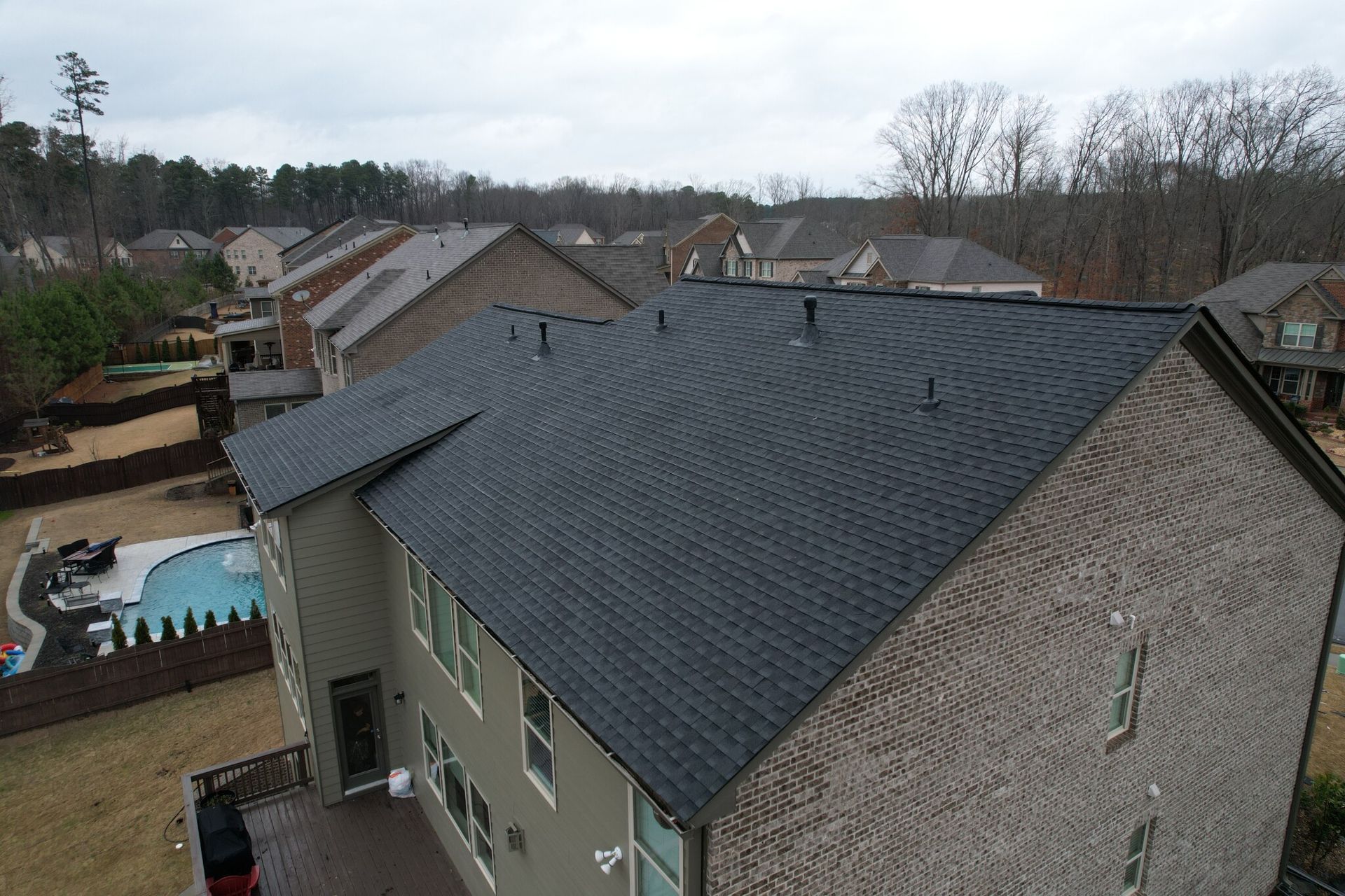 An aerial view of a house with a black roof and a pool.