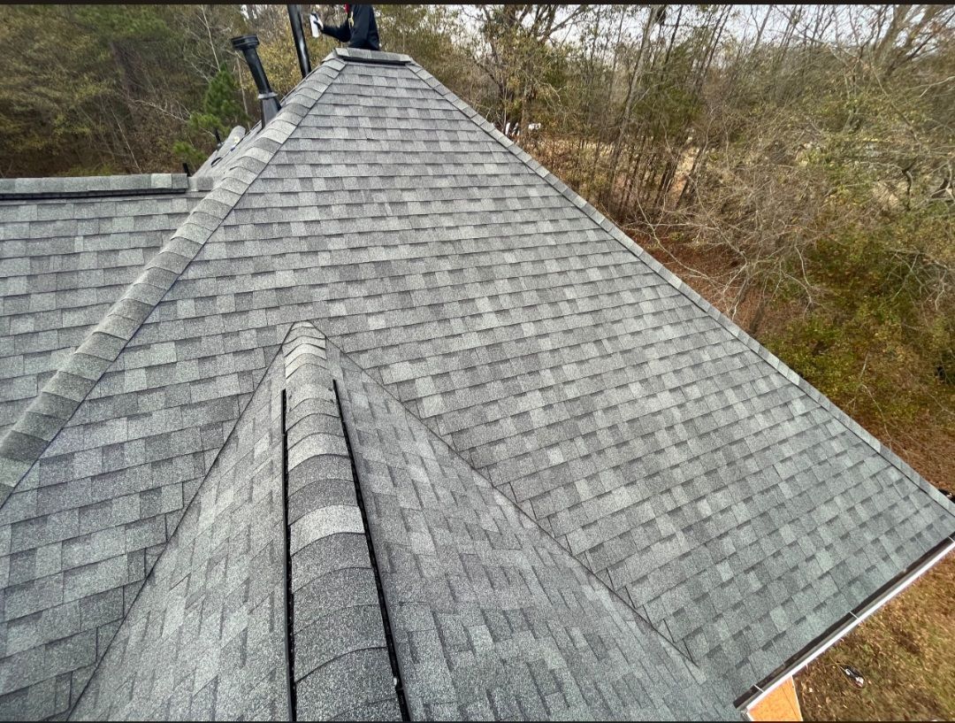 A roof with a lot of shingles on it and trees in the background.