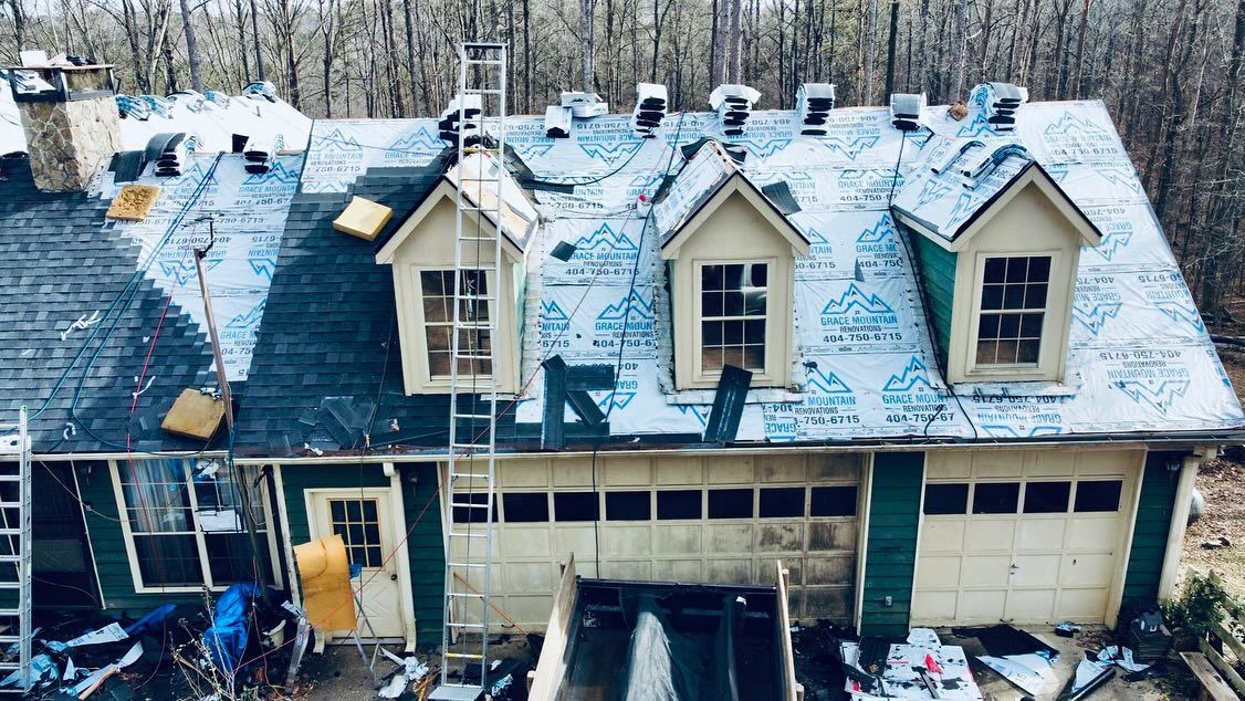 An aerial view of a house under construction with a roof being installed.