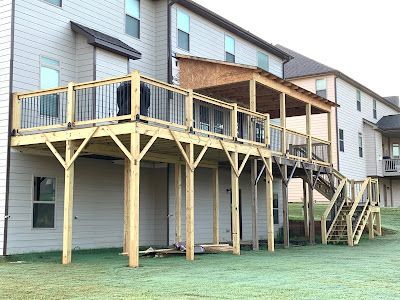 A large wooden deck with stairs is in front of a house.