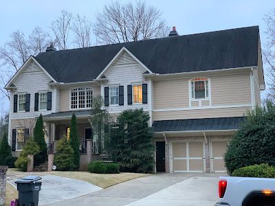 A large house with a black roof and a white truck parked in front of it.