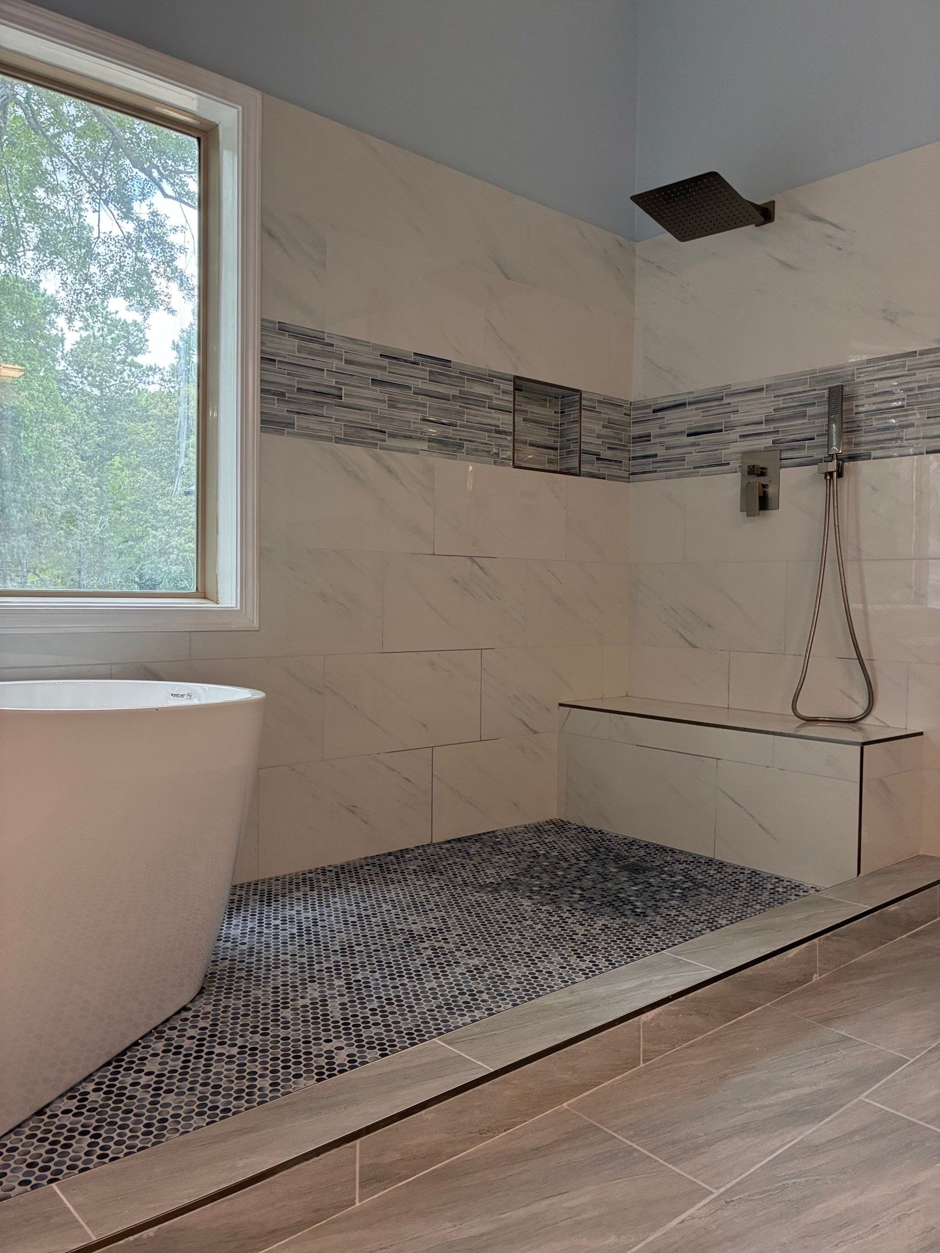 Modern bathroom with a stone-tiled shower floor, white walls, and a built-in bench.