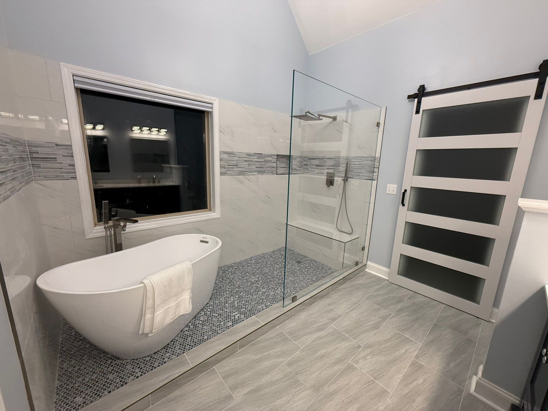 Modern bathroom with a soaking tub, glass shower, and barn door.