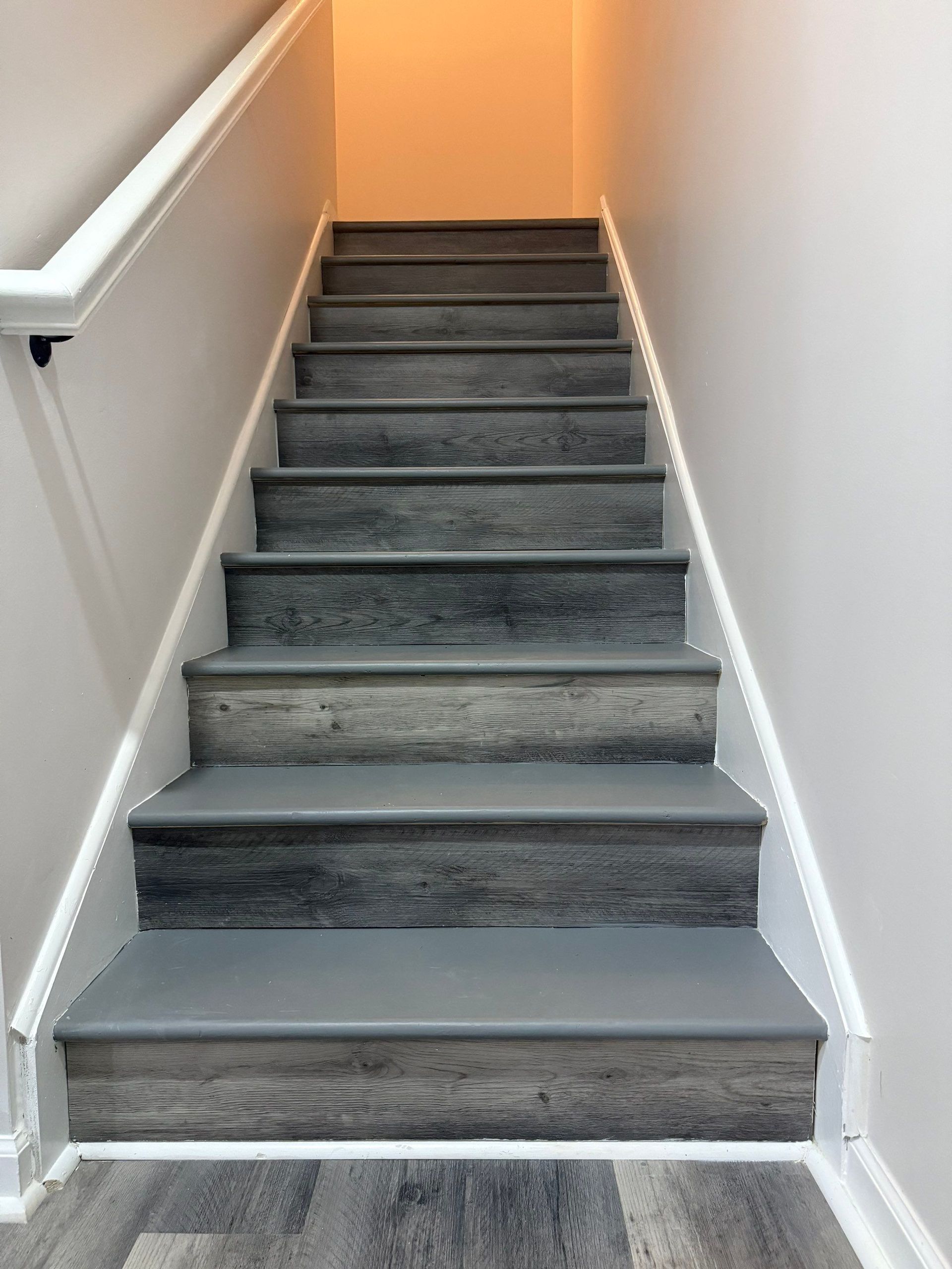 Wooden stairs leading upwards, with white banister on the left.