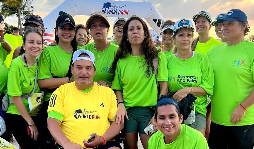 A group of people wearing green shirts are posing for a picture.