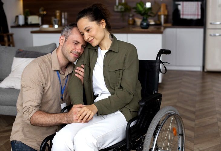 A man is hugging a woman in a wheelchair.