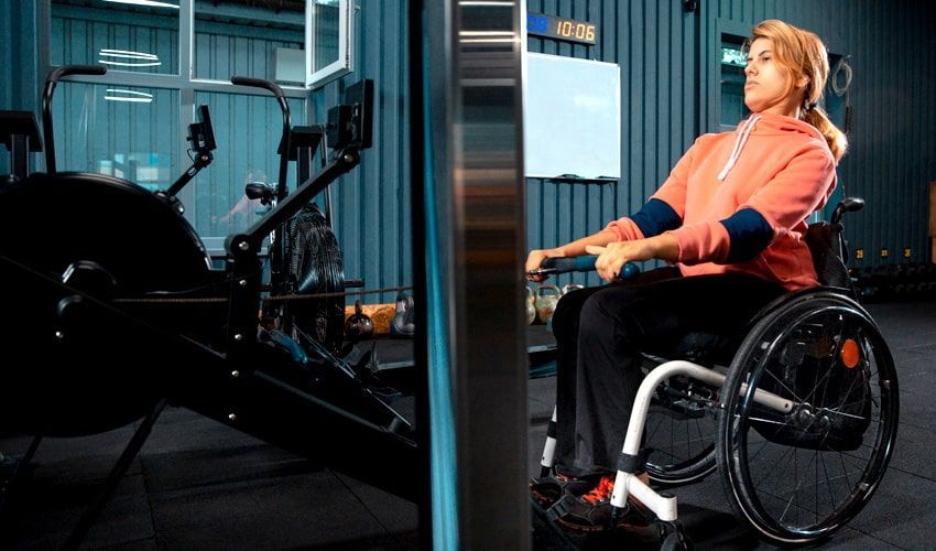 A woman in a wheelchair is using a machine in a gym.