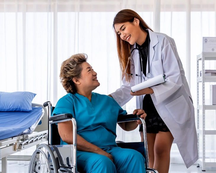 A doctor is talking to an elderly woman in a wheelchair.