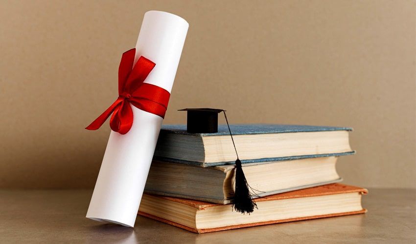 A diploma is sitting on top of a stack of books.