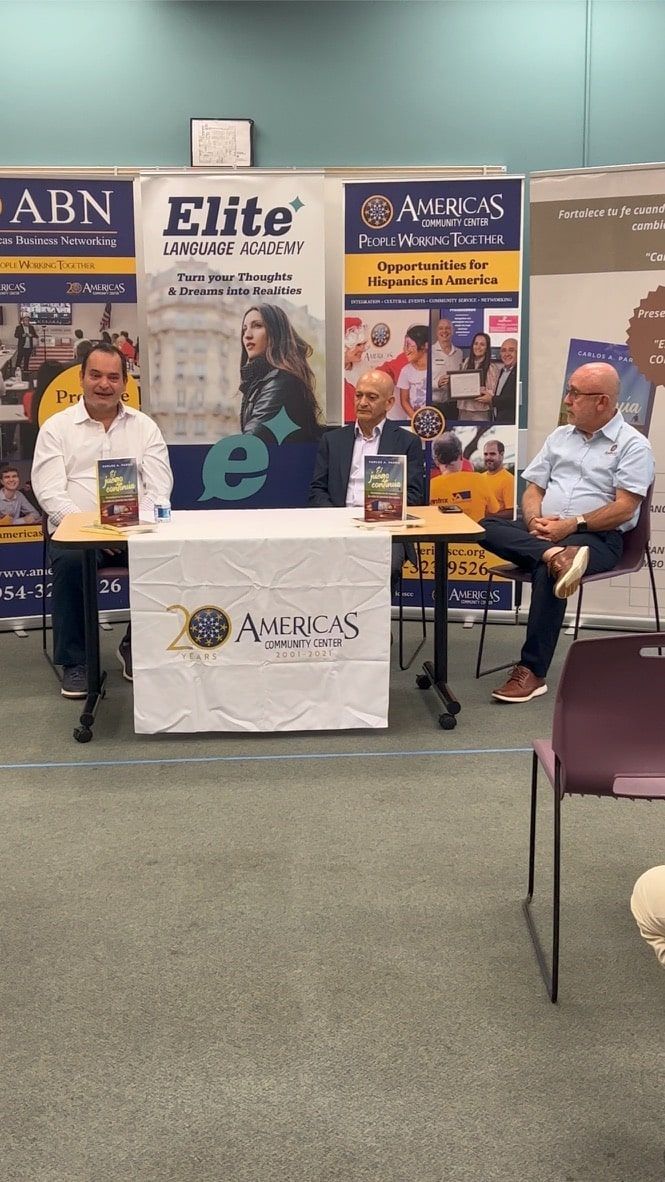 Two men are sitting at tables in front of a sign that says elite.