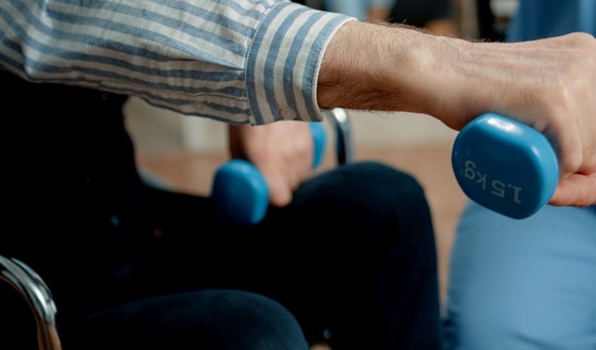 A man in a wheelchair is holding a blue dumbbell.