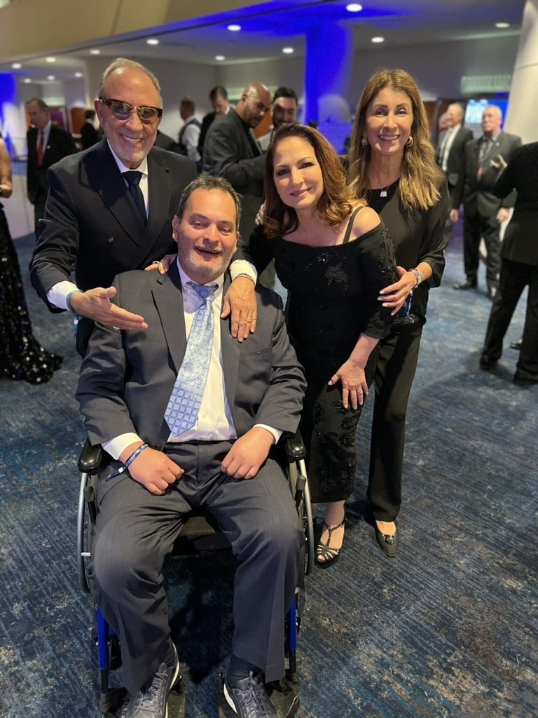 A man in a wheelchair is posing for a picture with three other people.