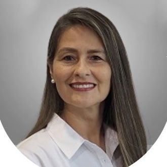 A woman with long hair is smiling and wearing a white shirt.