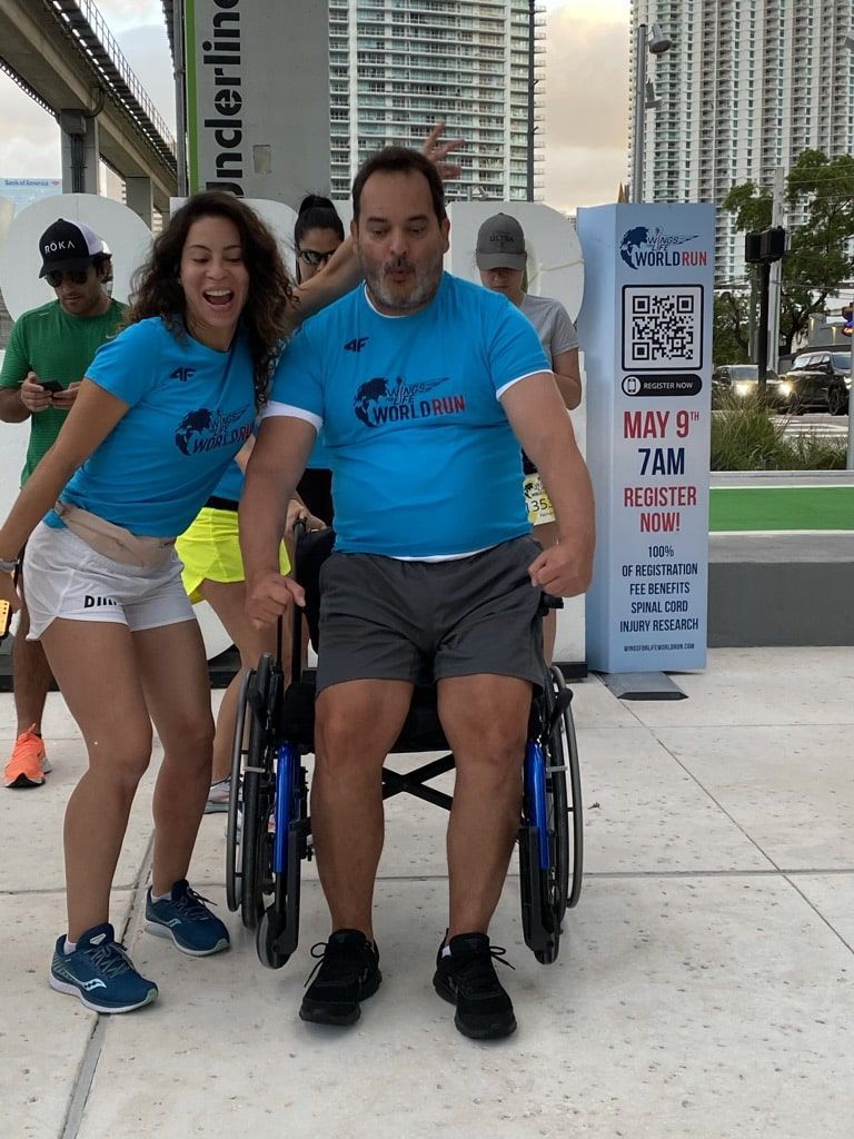 A man in a wheelchair is standing next to a woman in a blue shirt.