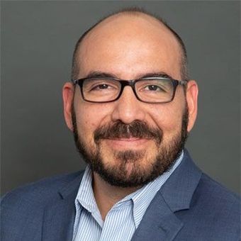 A bald man with a beard and glasses is smiling for the camera.