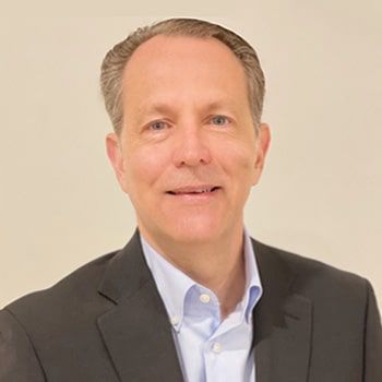 A man in a suit and blue shirt is smiling for the camera.