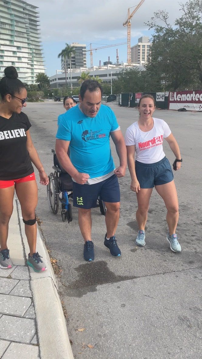 A man in a wheelchair is walking with two women.