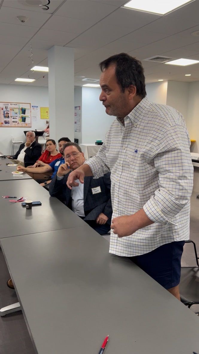 A man is standing in front of a group of people sitting at tables.