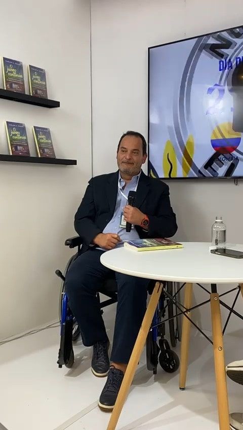 A man in a wheelchair is sitting at a table with a microphone.
