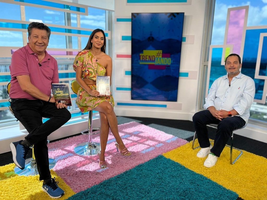 A woman is sitting on a stool next to two men in a studio.