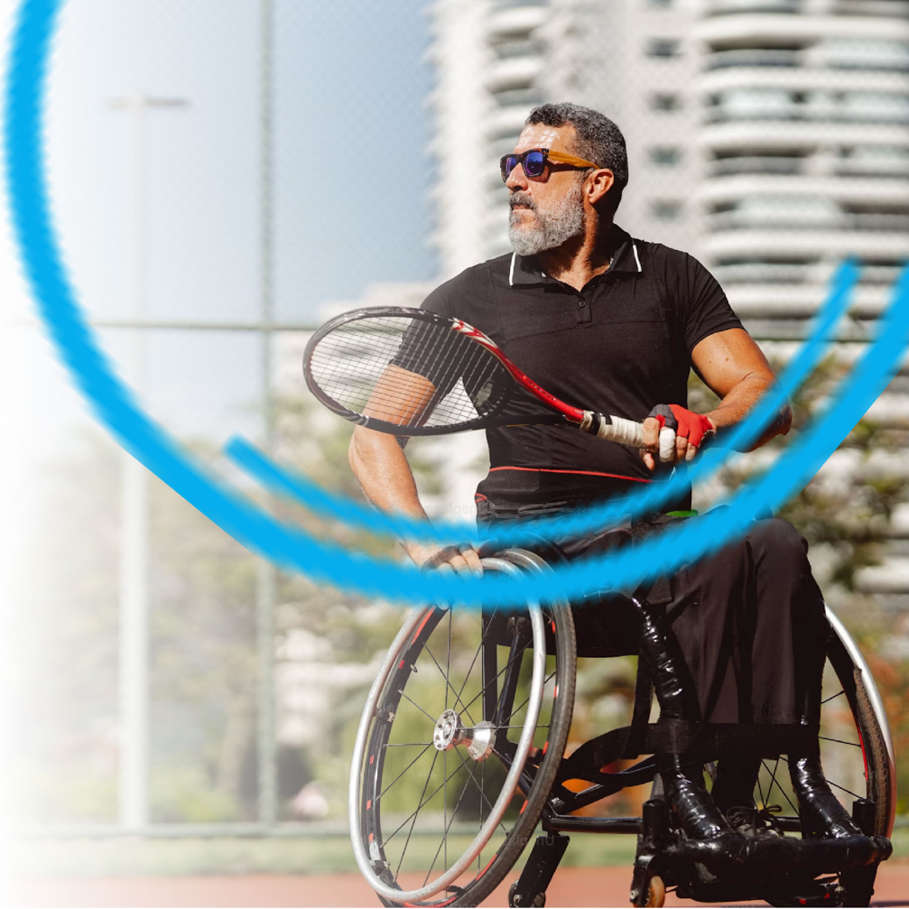 Man in a wheelchair holding a tennis racket on a court, looking off-camera.