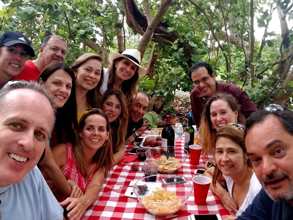 A group of people are posing for a picture at a picnic table.