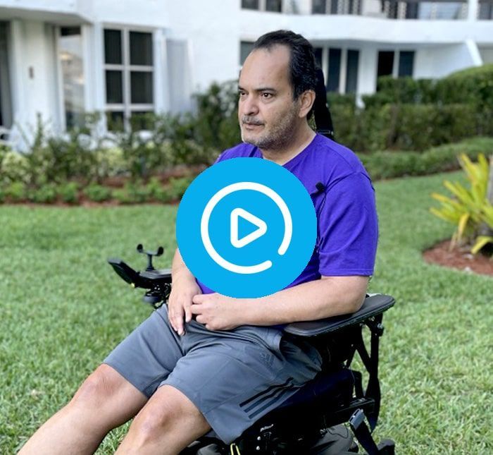 A man in a purple shirt is sitting in a wheelchair