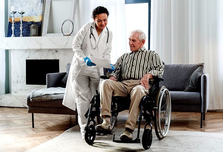 A nurse is helping an elderly man in a wheelchair.