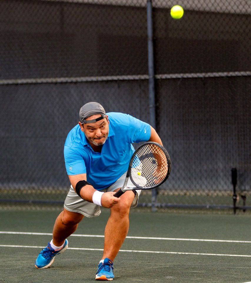 A man in a blue shirt is playing tennis on a court