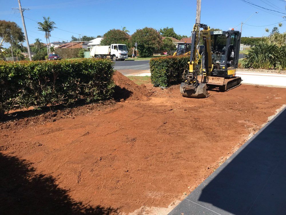 A Small Excavator is Digging a Hole in the — Greener Gardens Gardening Service In Thrumster, NSW
