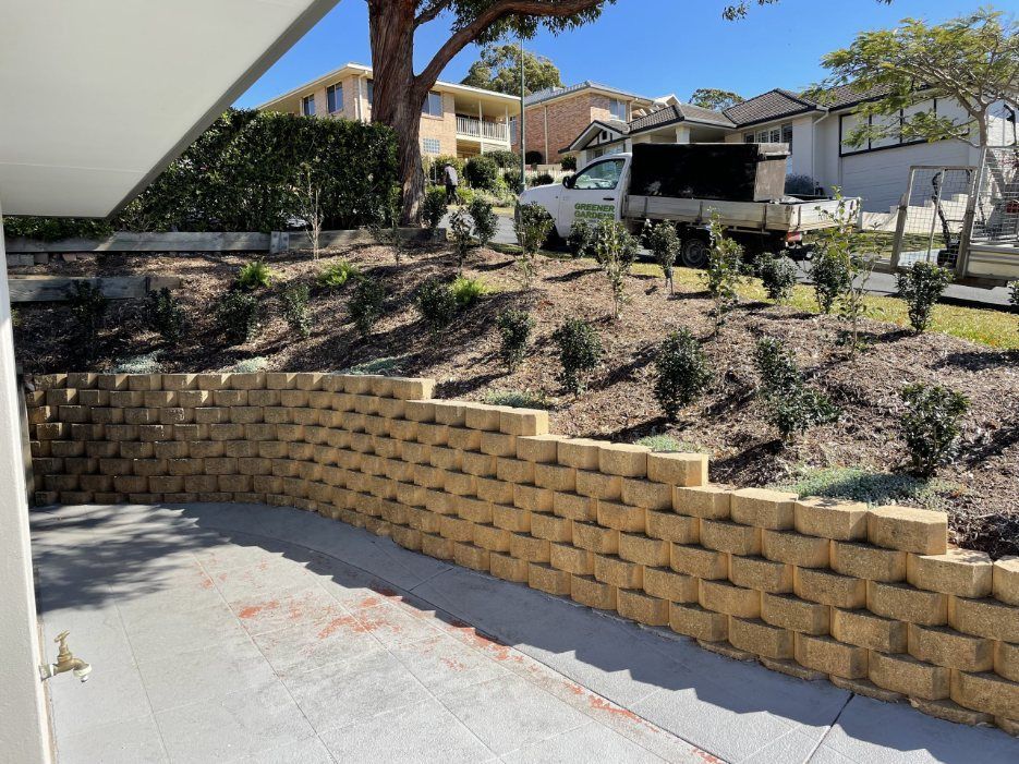 A Brick Wall is Being Built in Front of a House — Greener Gardens Gardening Service In Thrumster, NSW