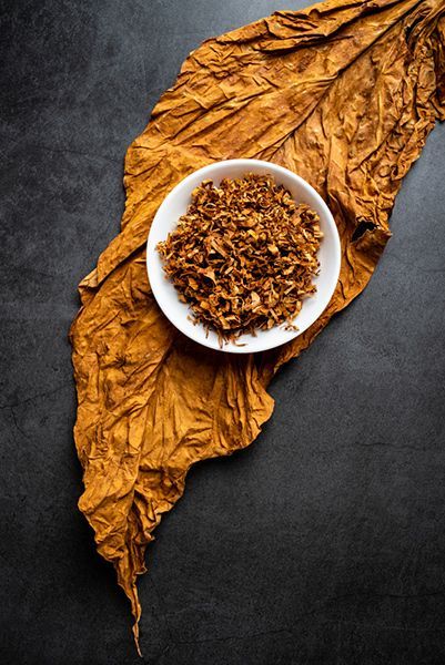 A Bowl of Dried Tobacco is Next to A Leaf on A Table — Mini Market Townsville Smoke Shop in Townsville City, QLD