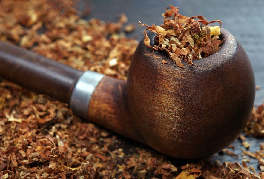 A Wooden Pipe Filled with Tobacco Is Sitting on Top of A Pile of Tobacco — Mini Market Townsville Smoke Shop in Townsville City, QLD