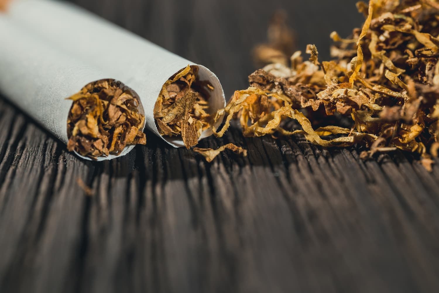 Three Cigarettes and Tobacco Leaves on A Wooden Table — Mini Market Townsville Smoke Shop in Townsville City, QLD