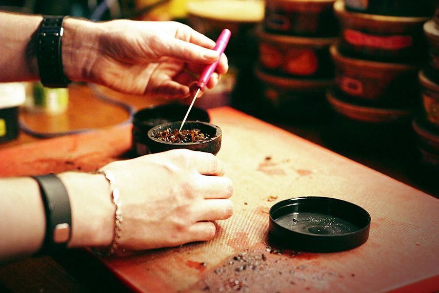 A Person Is Grinding Tobacco in A Grinder on A Table — Mini Market Townsville Smoke Shop in Townsville City, QLD