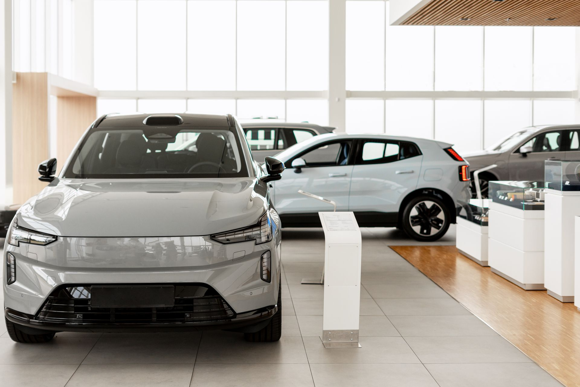 Gray electric SUV in a showroom, other cars visible, bright interior.