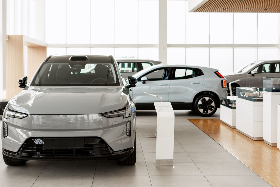 Gray electric SUV in a showroom, other cars visible, bright interior.